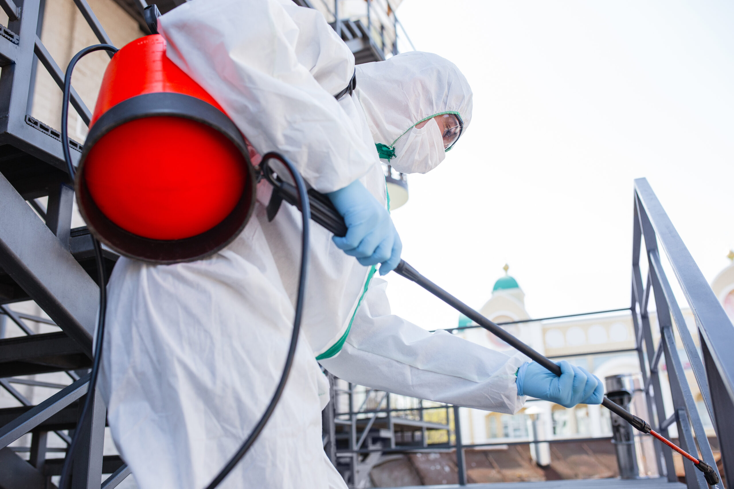 Coronavirus Pandemic. A disinfector in a protective suit and mask sprays disinfectants in the room.